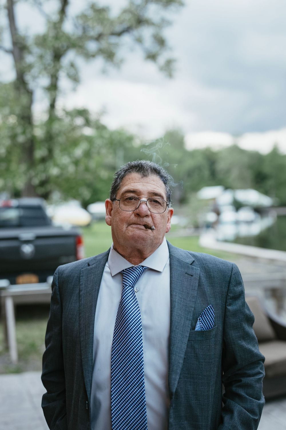 Portrait series of a guest in a gray suit and blue tie at an outdoor event.