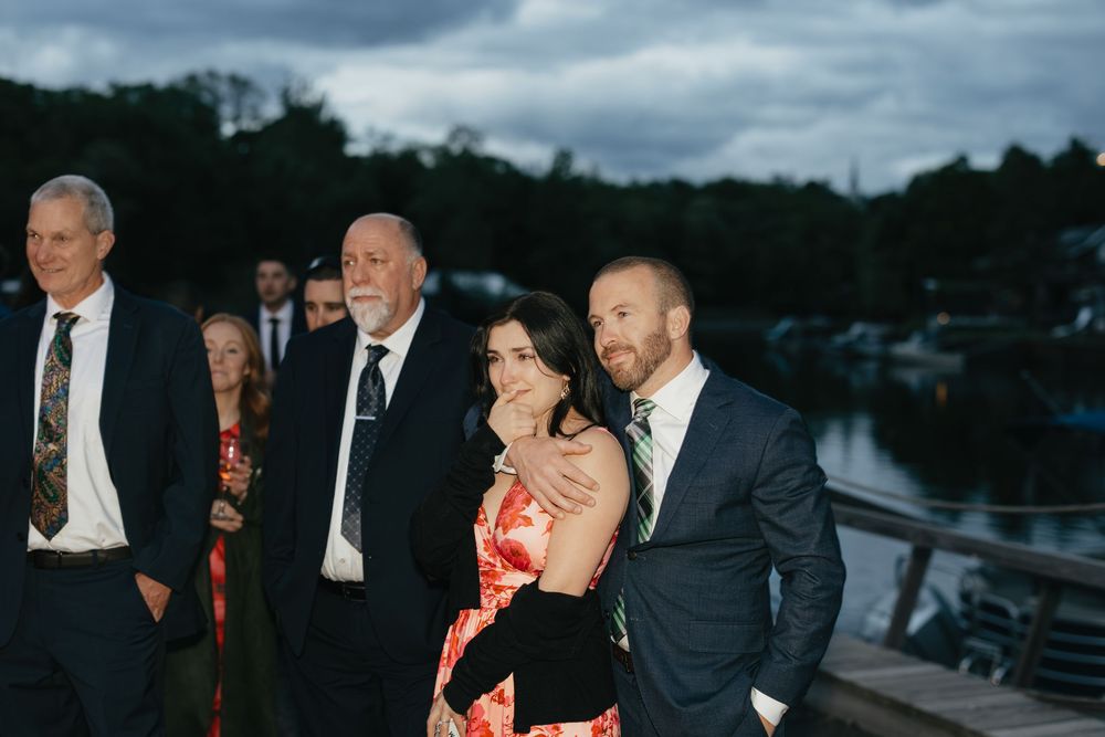 A wedding celebration at dusk with guests gathered outdoors under dramatic cloudy skies.