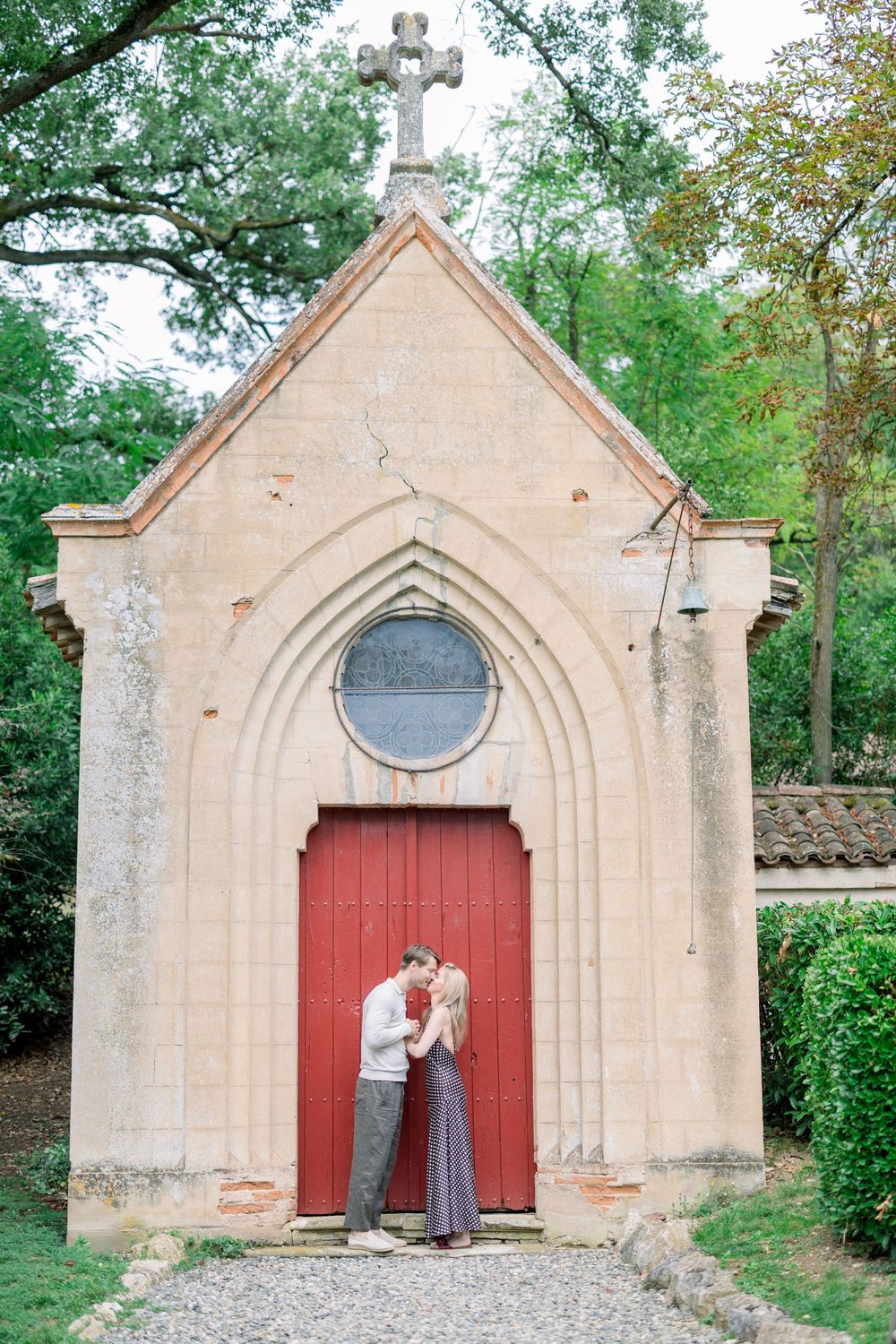 Romantic sequence of couple by vintage stone chapel with red door.