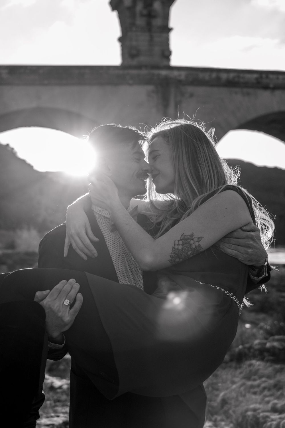 Romantic silhouettes embrace against dramatic backlit stone architecture.