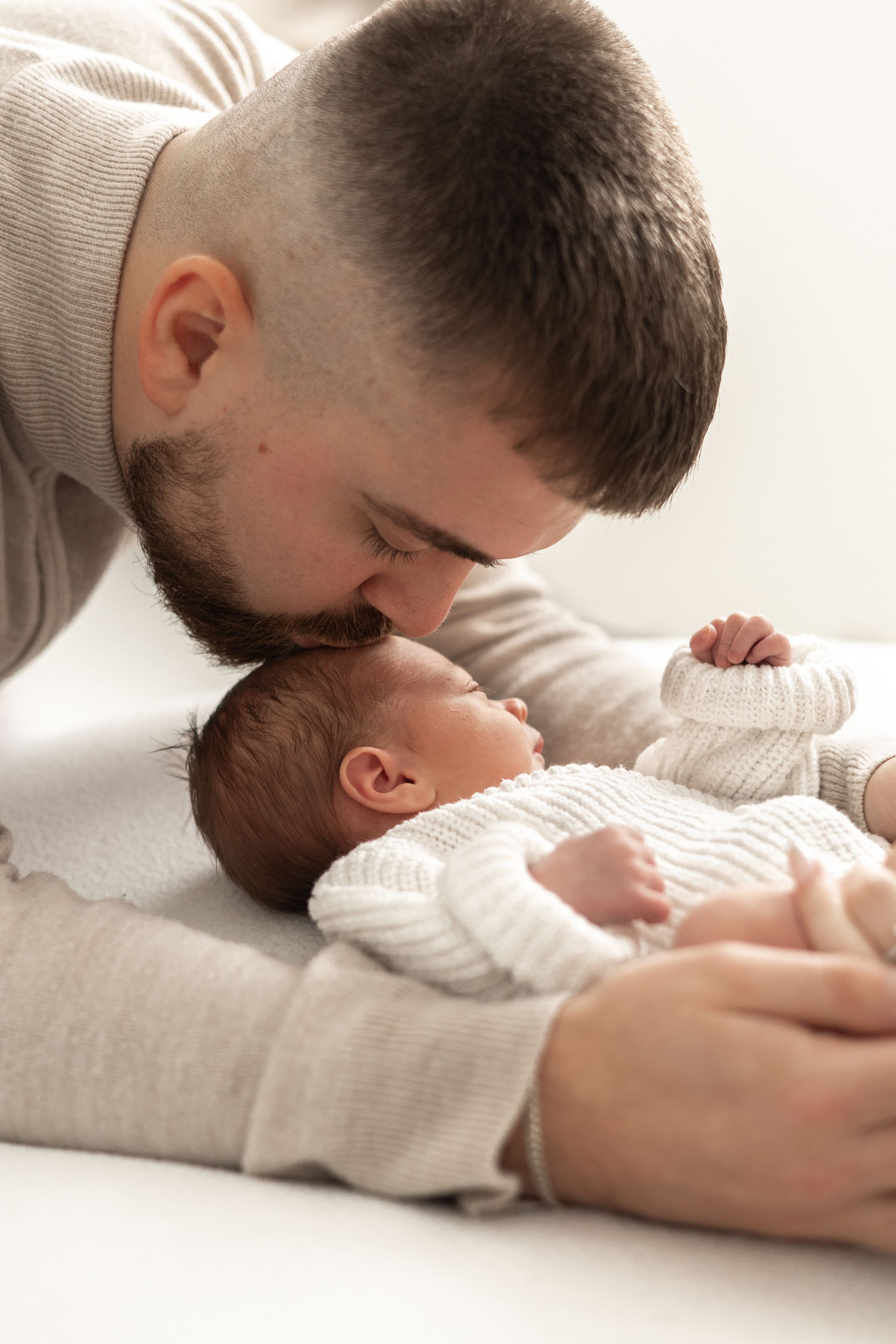 A father gently kisses his newborn baby newborn photoshoot Nottingham natural light