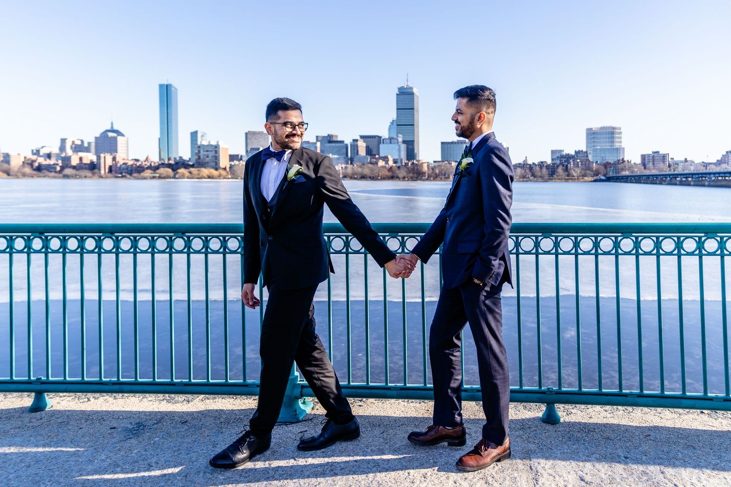 LGBTQ+ couple walking along the waterfront with the Boston skyline in Boston, MA.