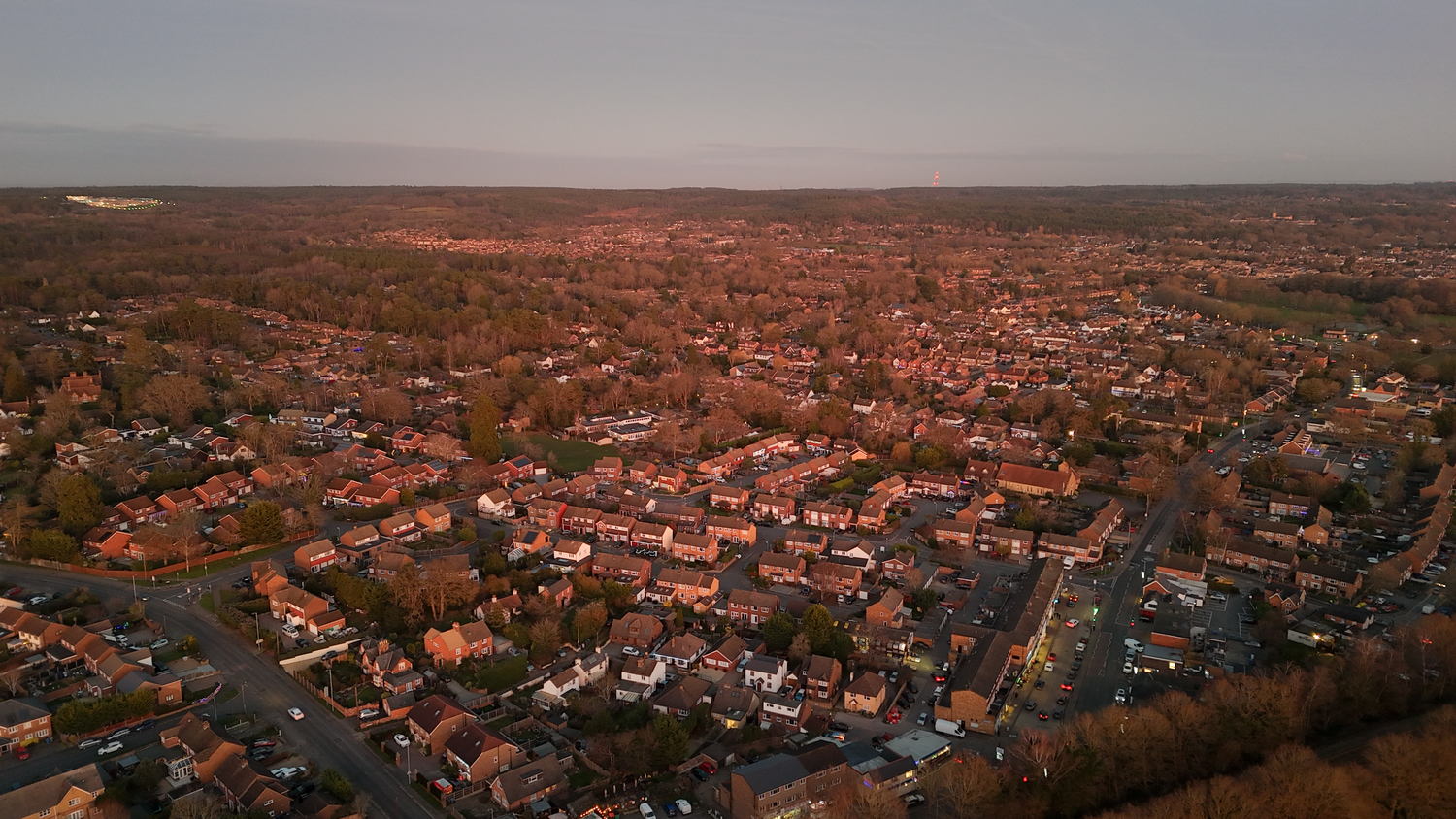 Panoramic aerial view of a densely populated suburban residential area with red-tiled roofs stretching to the horizon.