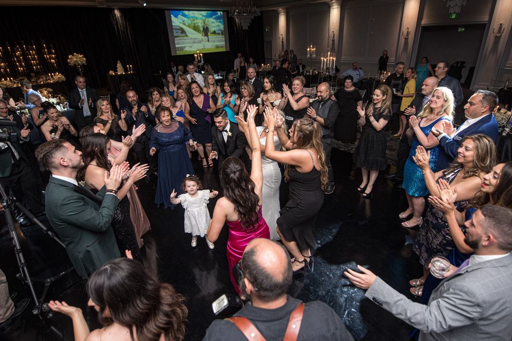 Lively wedding reception dance floor filled with celebrating guests and couple in center.