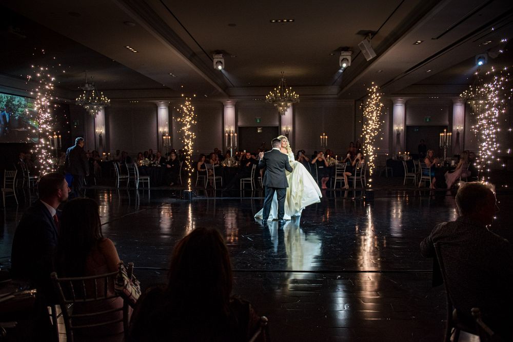 Bride and groom share intimate first dance with sparkling fireworks displays in a dimly lit ballroom.