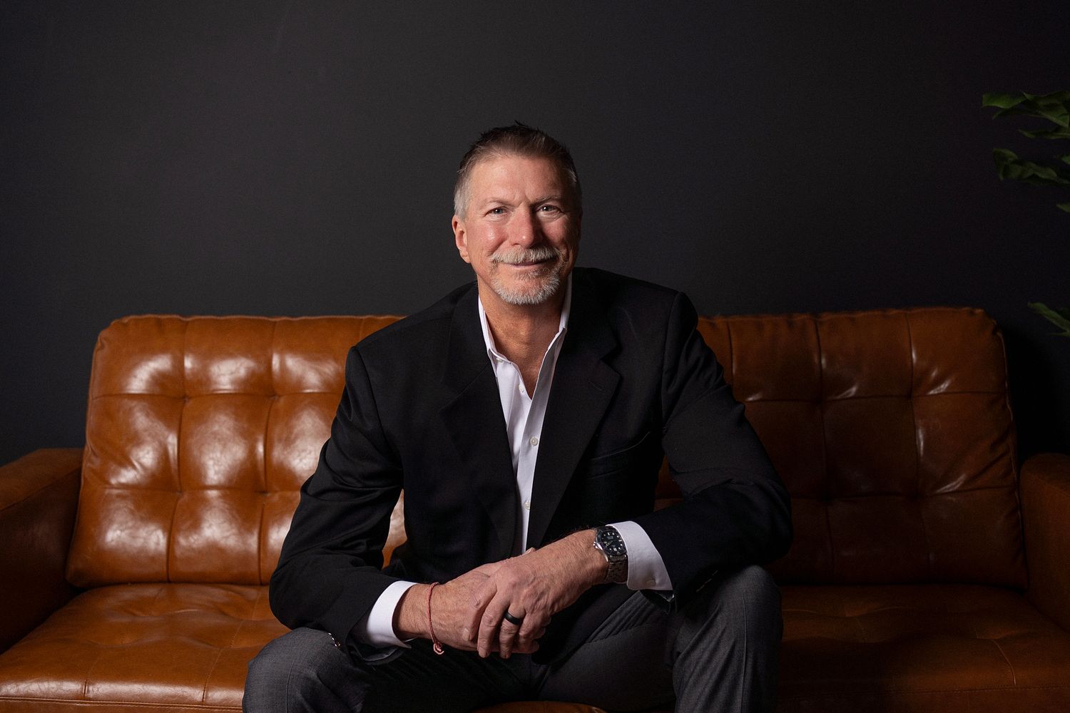 Professional portrait series showing person in navy blazer and black top sitting at desk in office setting.