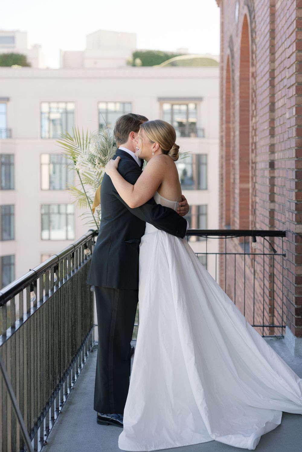 A romantic moment between newlyweds embracing on an urban balcony.