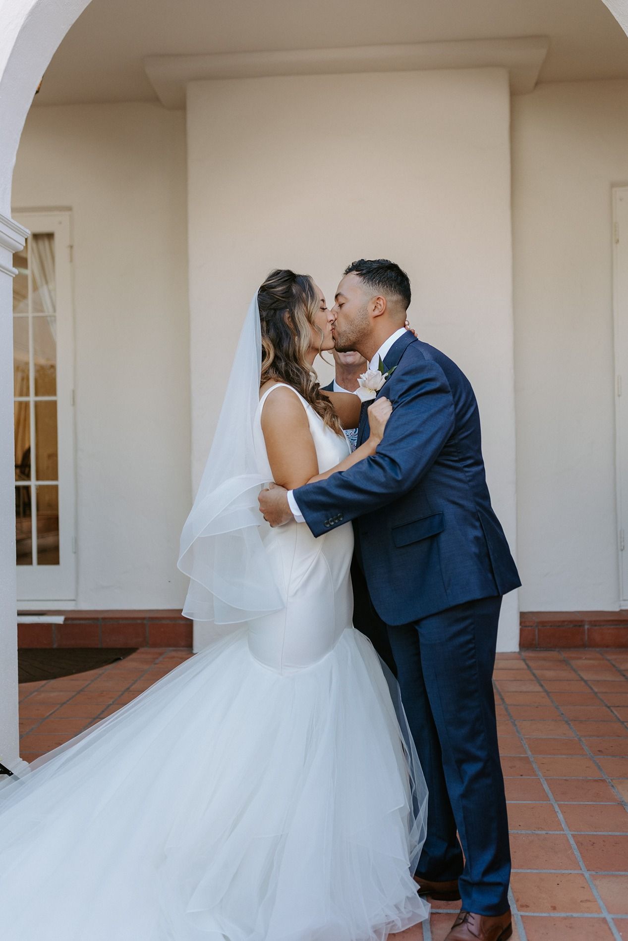 Bride and groom share a romantic kiss outdoors, bride in mermaid gown with veil, groom in navy suit at Darlington House.