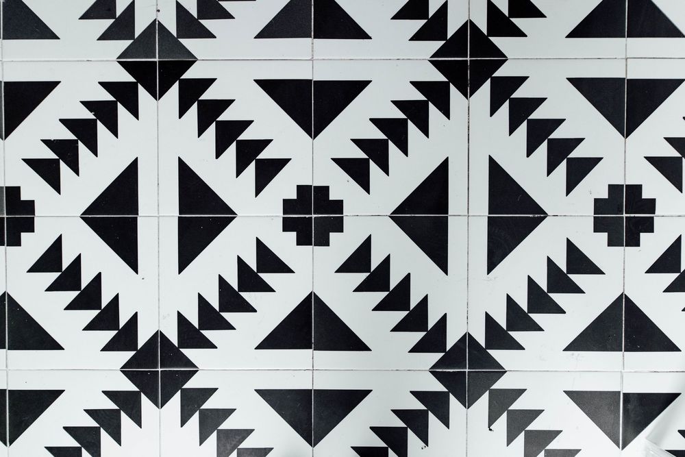 Black and white geometric patterned cement tiles with triangles and diamond shapes in a repeating motif.