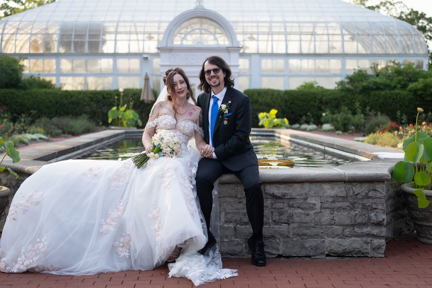 Bride and groom posing together in front of a fountain at a botanical garden wedding venue in Toledo Zoo Wedding Venue