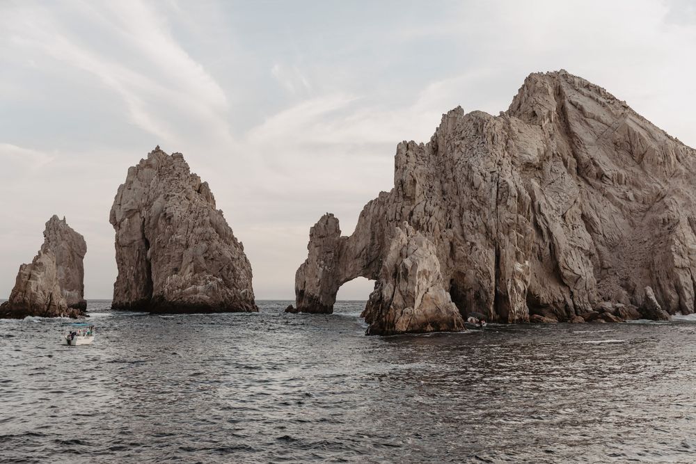 Dramatic rock formations and natural stone arch at El Arco de Cabo San Lucas in Mexico against cloudy sky.