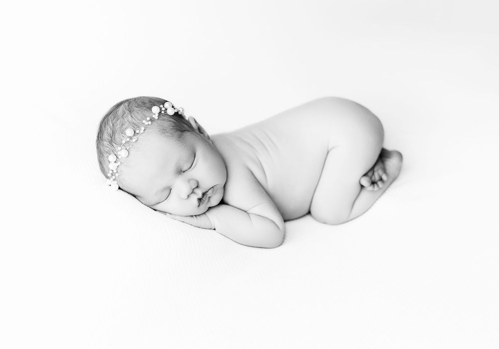 Black and white portrait of a sleeping newborn baby lying on their side in a peaceful curled position in Portsmouth Ohio