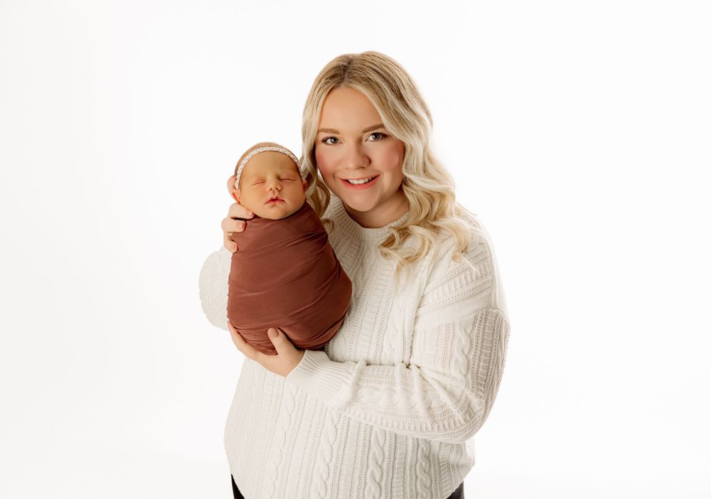 Mother in white sweater holds swaddled newborn against white background in Scioto County Ohio.