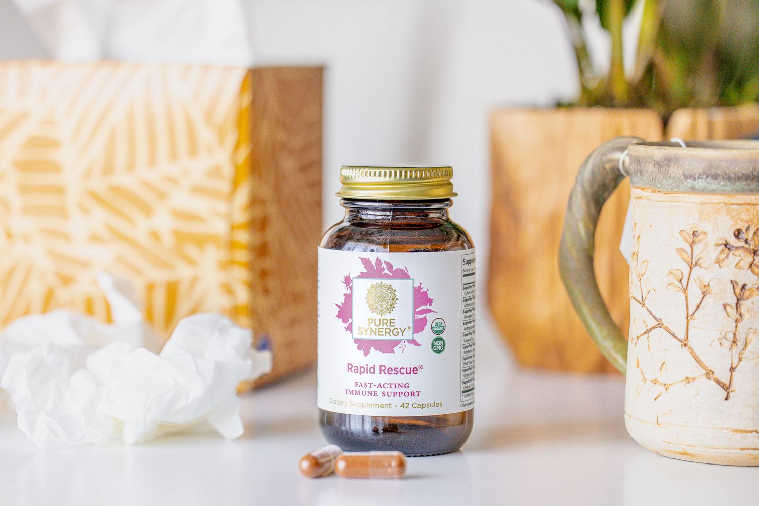 Herbal supplement bottle displayed with decorative elements and a ceramic mug.