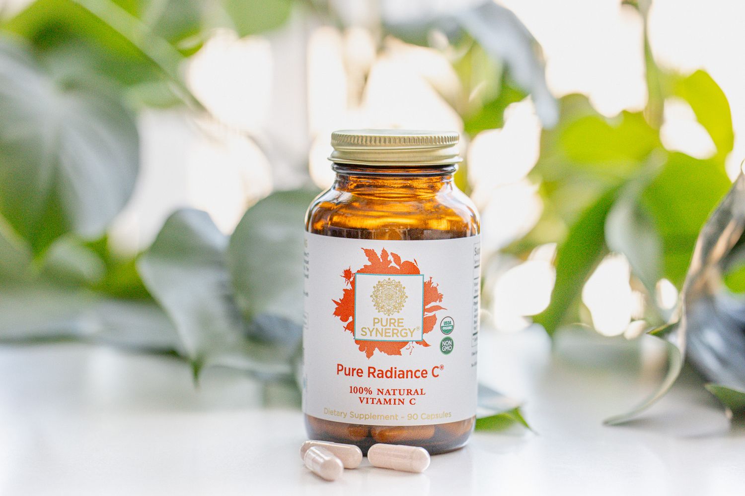 Vitamin C supplement bottle with orange branding displayed against blurred greenery.