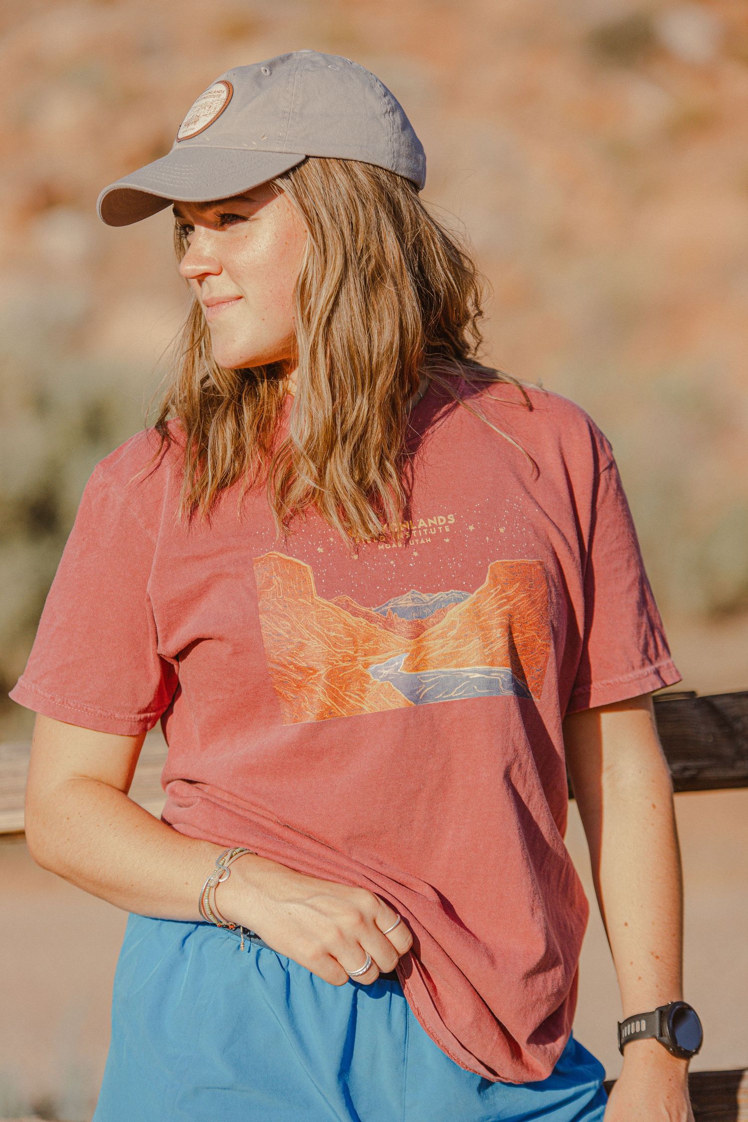 A casual outdoor shot showing a t-shirt with desert graphic and baseball cap against a natural backdrop.