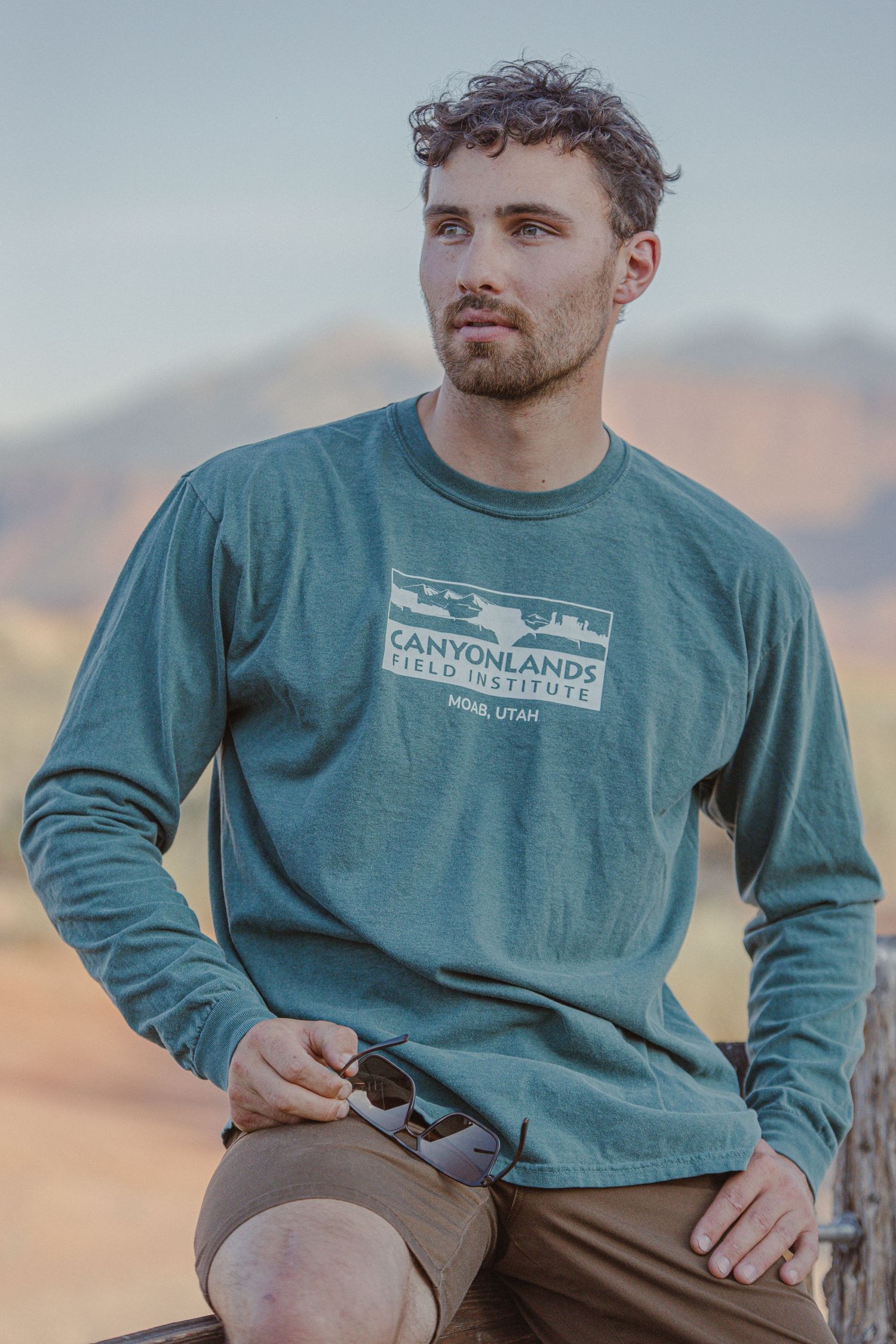 Canyon Country gear promotion showing model against desert landscape backdrop.