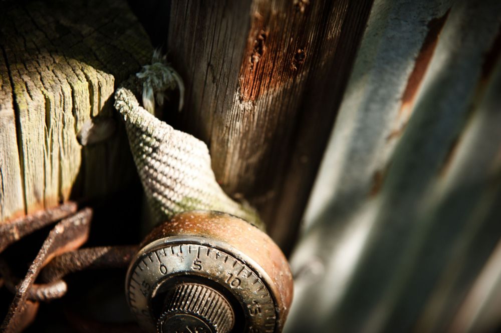 Close-up of a rusty padlock on and old rusted metal shed with a wooden door