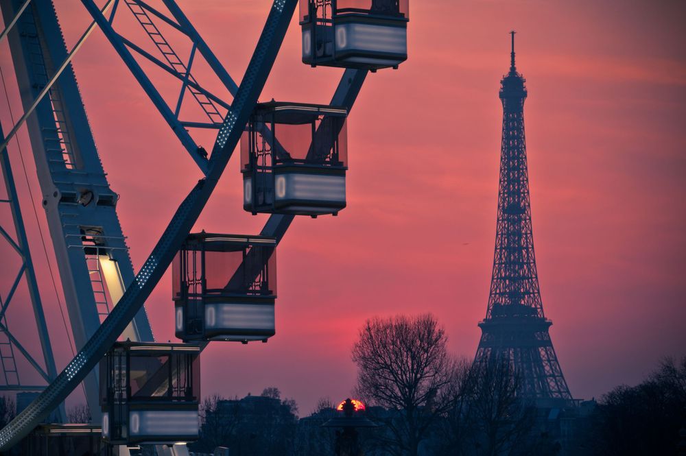Ferris Wheel in Paris, France in front of the Eiffel Tower at dusk with a pink sunset