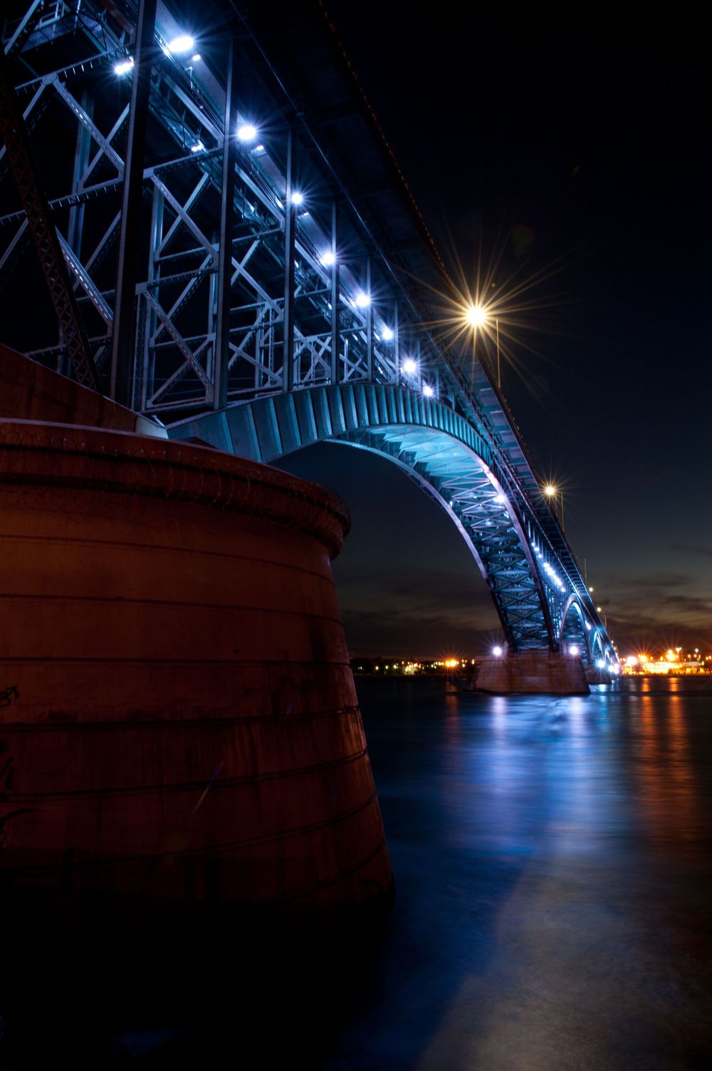 The Peace Bridge from underneath between Buffalo, NY and Fort Erie, Ontario lit up blue at night