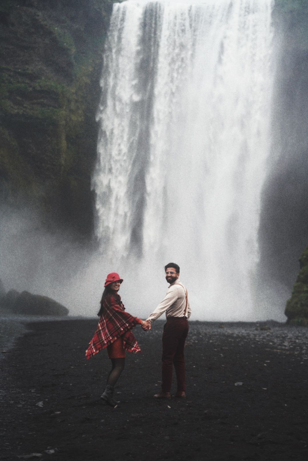 Couple running towards Skogafoss Iceland