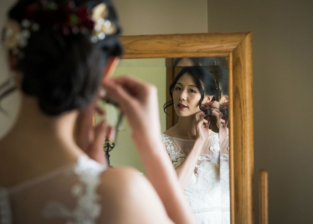 Getting ready scene with makeup application reflected in an elegant wood-framed mirror.