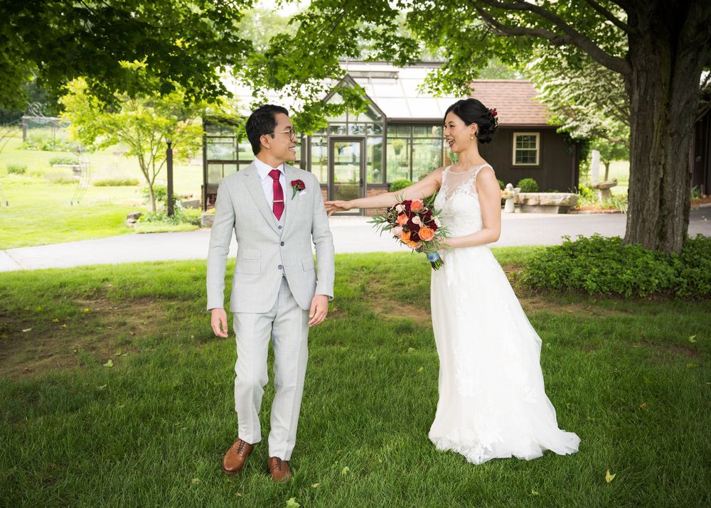 Wedding party taking outdoor photos under green trees on a sunny summer day.