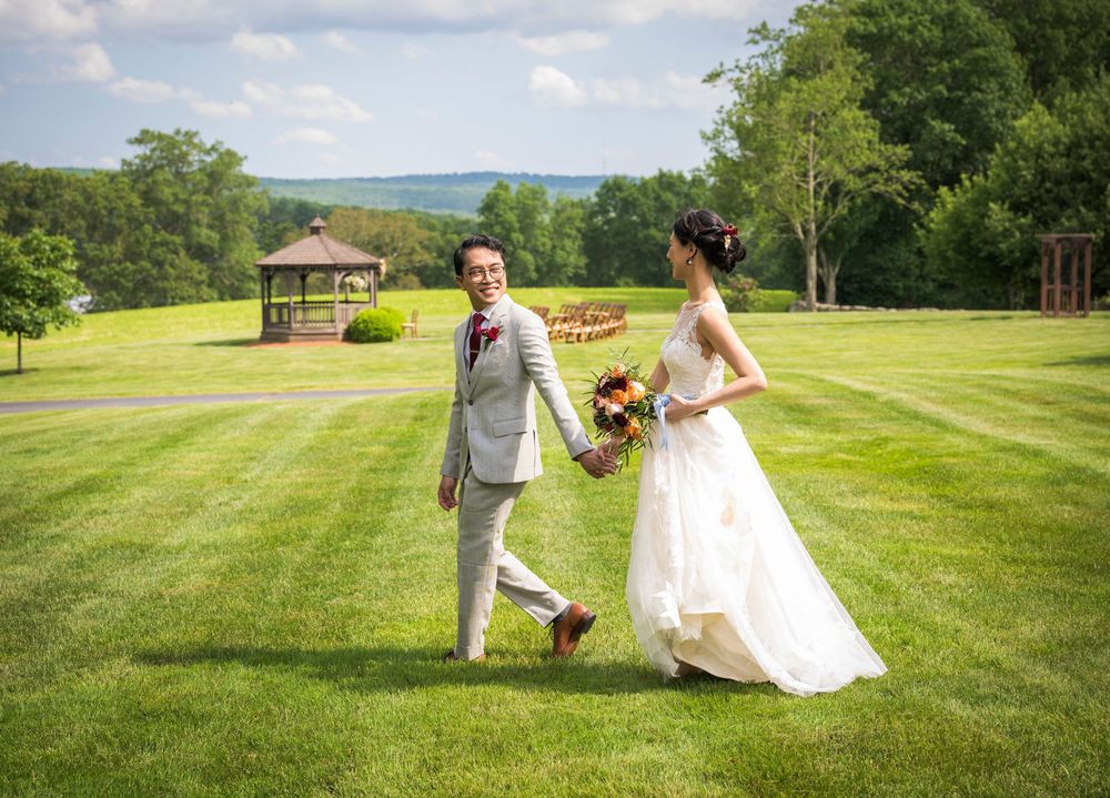 Wedding couple walking and posing together across a sweeping green hillside landscape.