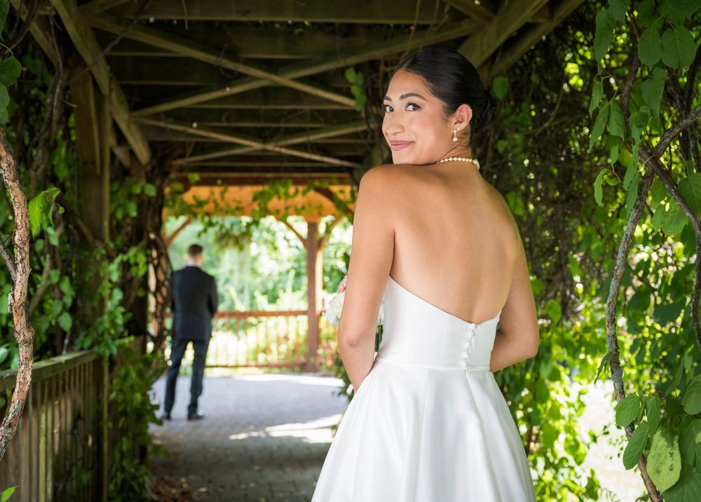 Couple shares romantic moment under garden pergola with climbing vines and natural lighting.