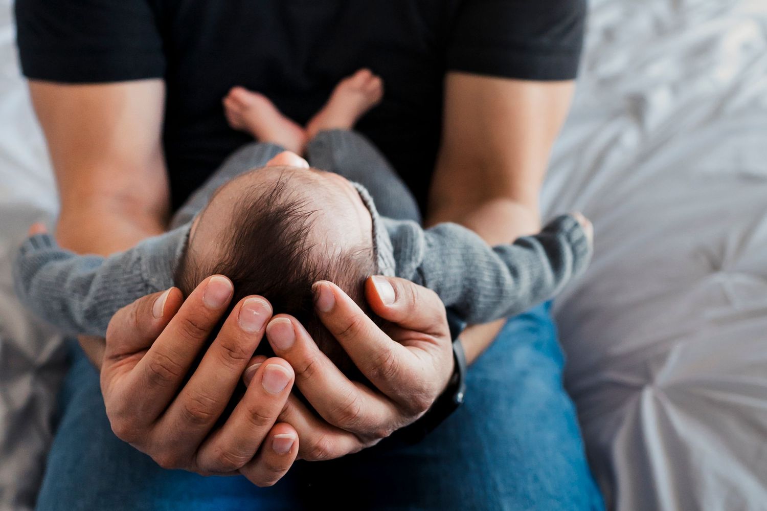 Four close-up photos showing hands holding fresh garlic bulbs against dark and light backgrounds.