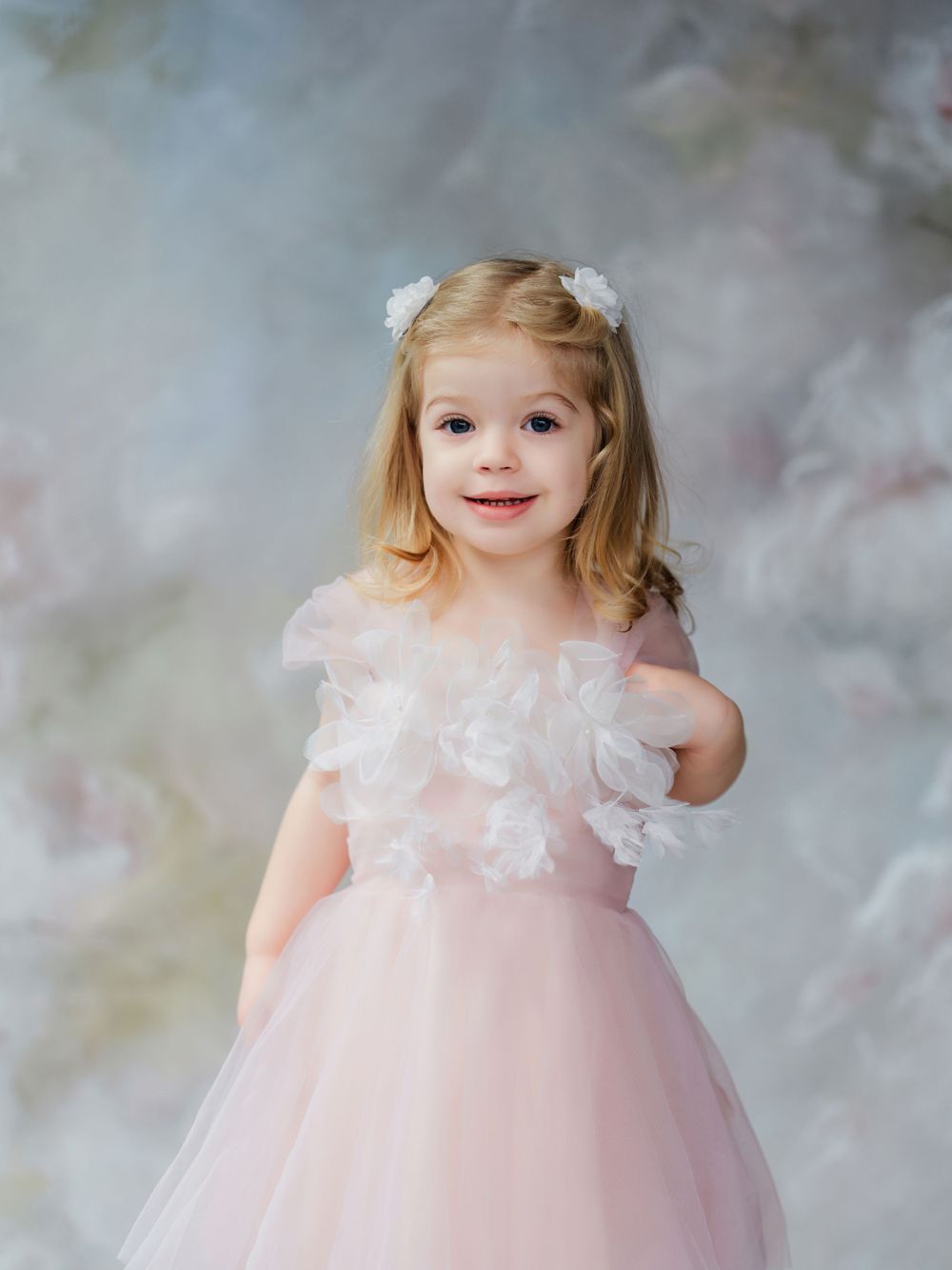 Small child wearing a dreamy pink tulle dress with white lace details poses in soft ethereal studio setting in Bellevue studio.