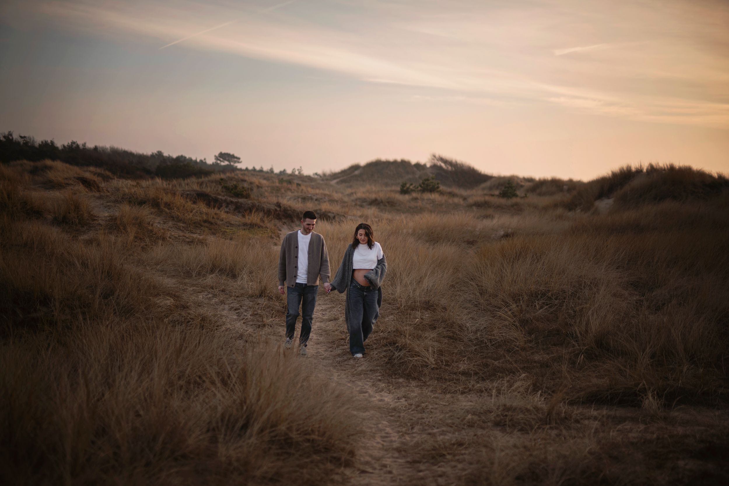 Couple walking together on sandy trail during golden sunset.