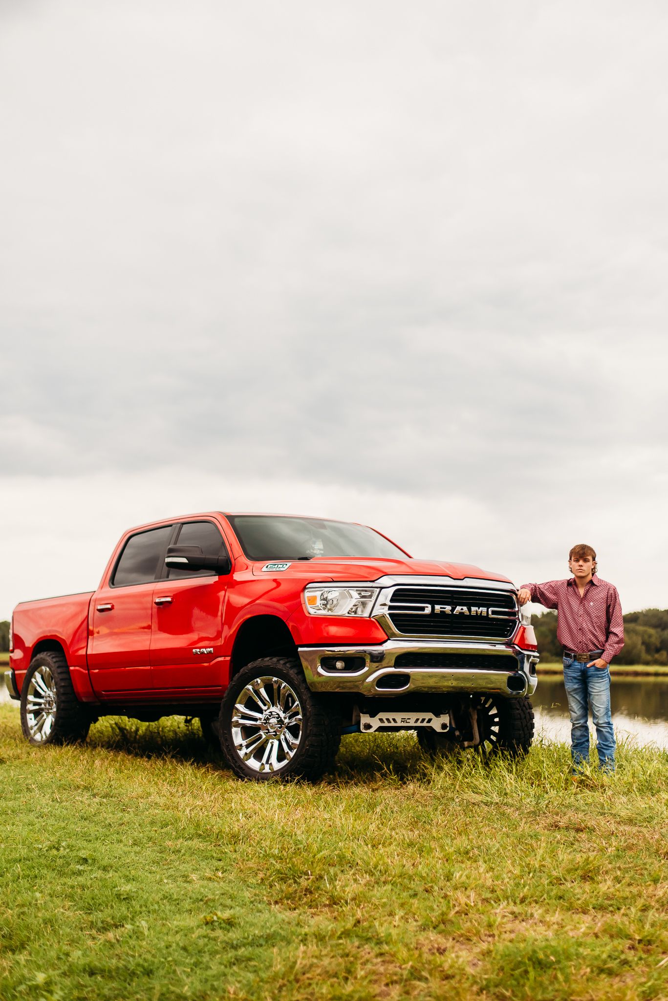 Red Ram pickup truck displayed on grass with moody sky background.