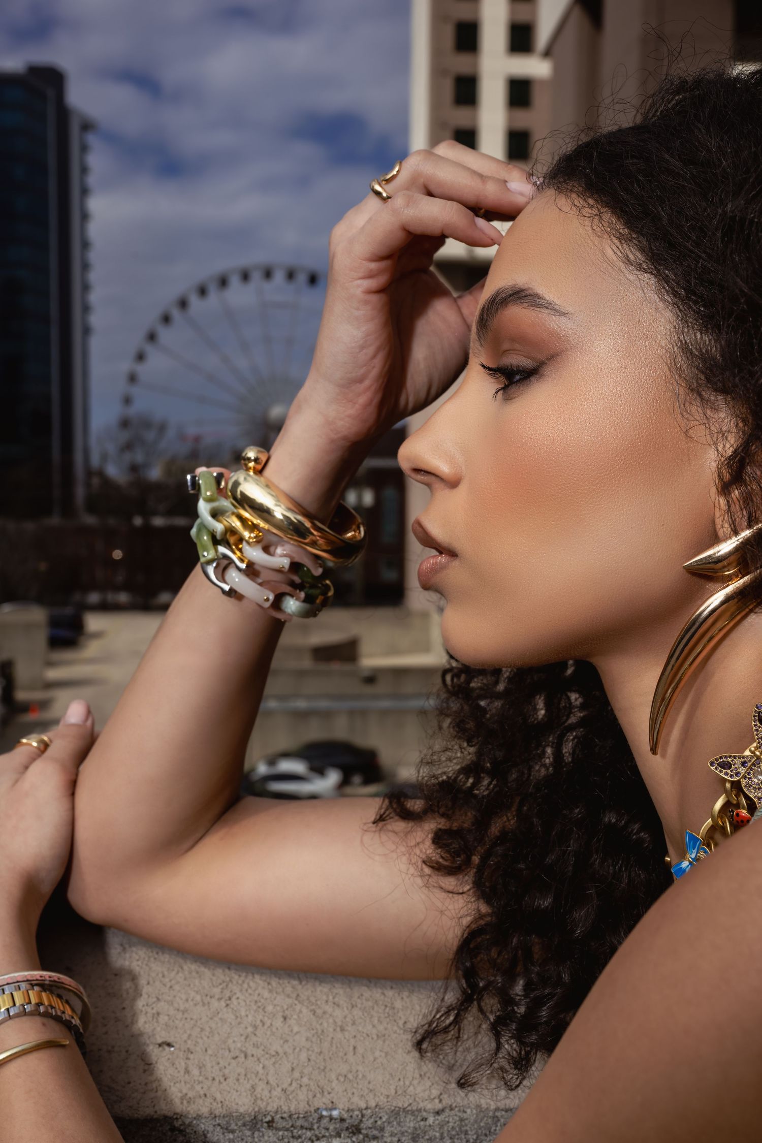 Fashion portrait featuring stylish jewelry and accessories against urban backdrop with Ferris wheel.