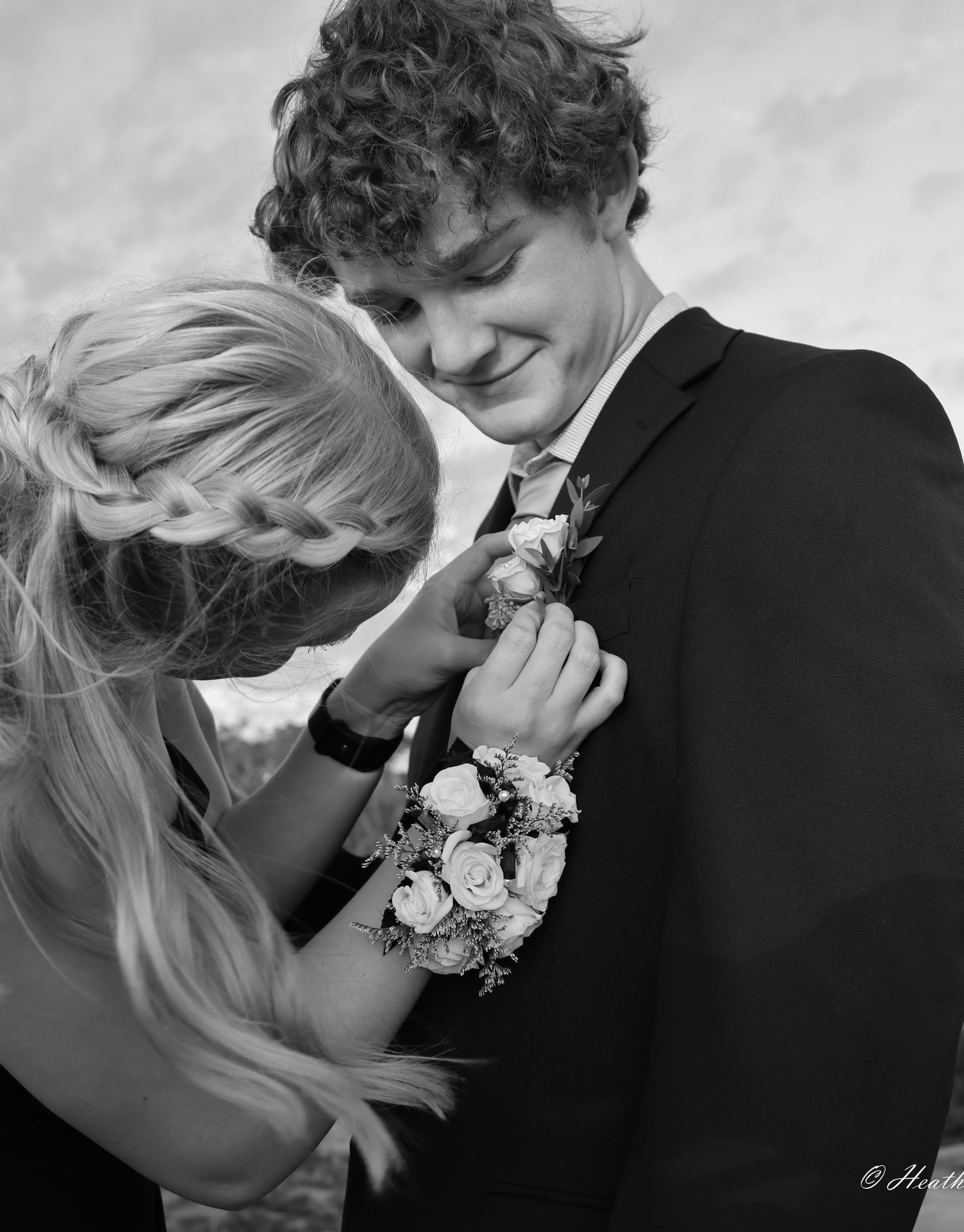 A beautiful young woman pins a corsage on her stunning prom date.