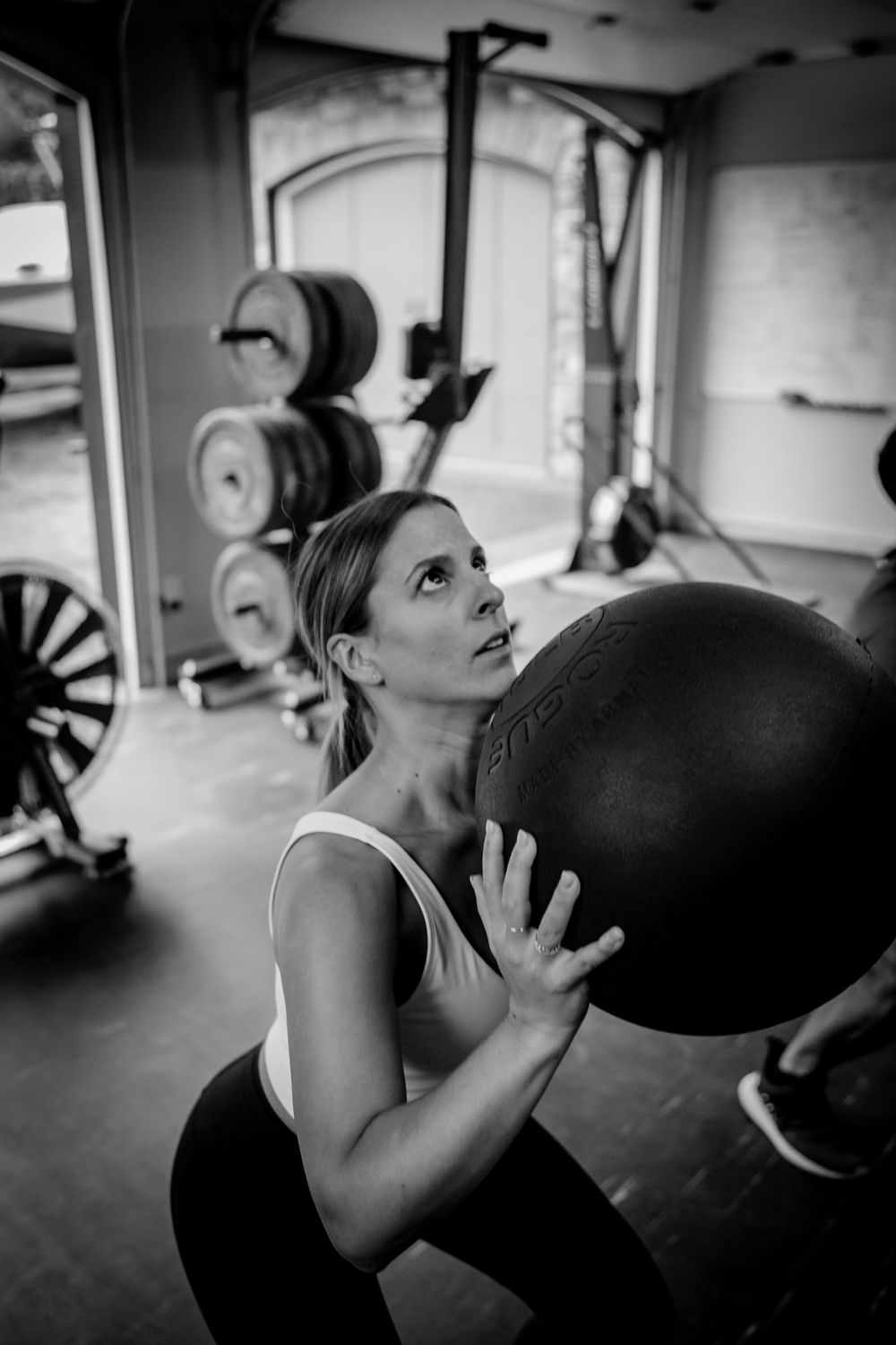 Athlete performing exercise with medicine ball in well-equipped gym space.