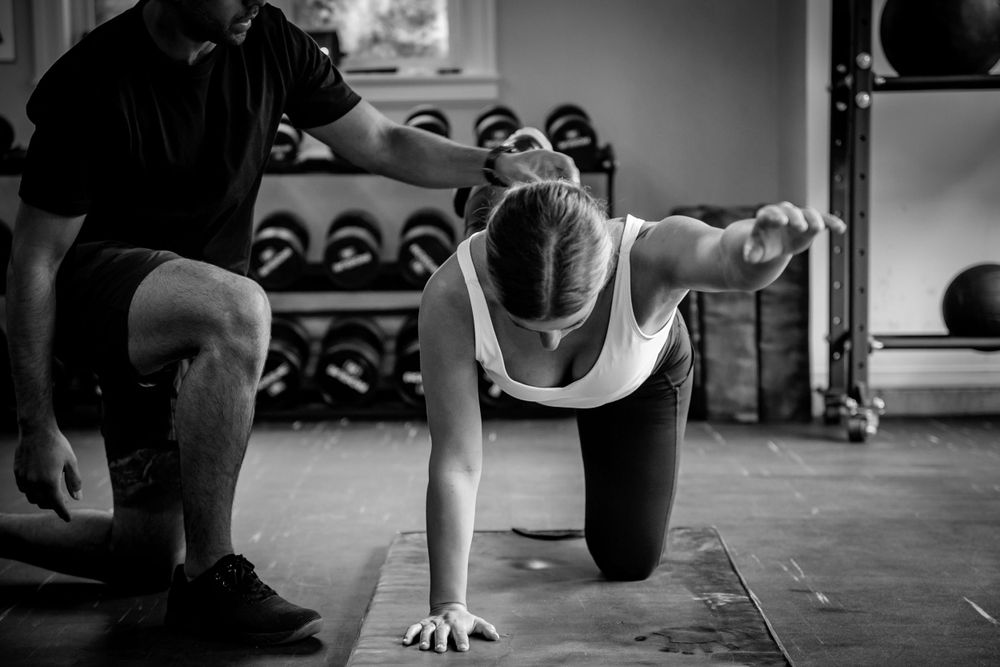 Fitness training session in a gym with exercise equipment visible in the background.