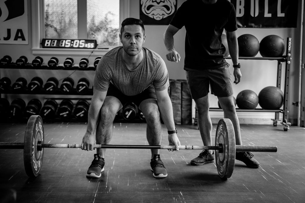 Weightlifter in proper form preparing to lift barbell in gym setting.
