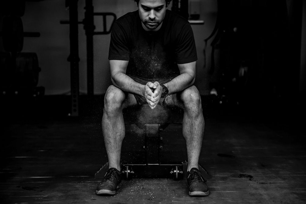 Athletic figure performing weightlifting exercise in dark gym setting.