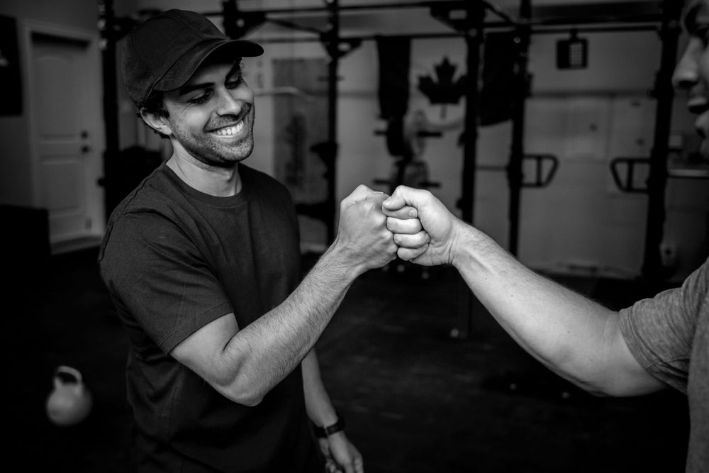 Two people sharing a celebratory fist bump in a gym environment.
