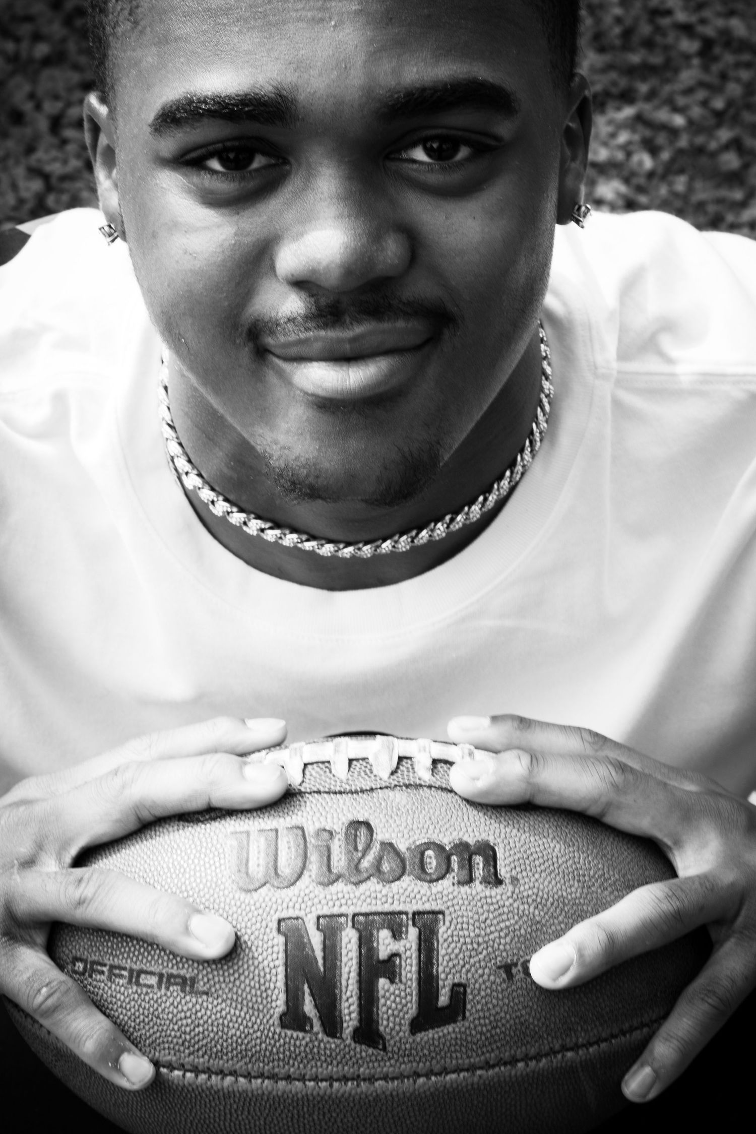 portrait of a young man gripping a football in black and white