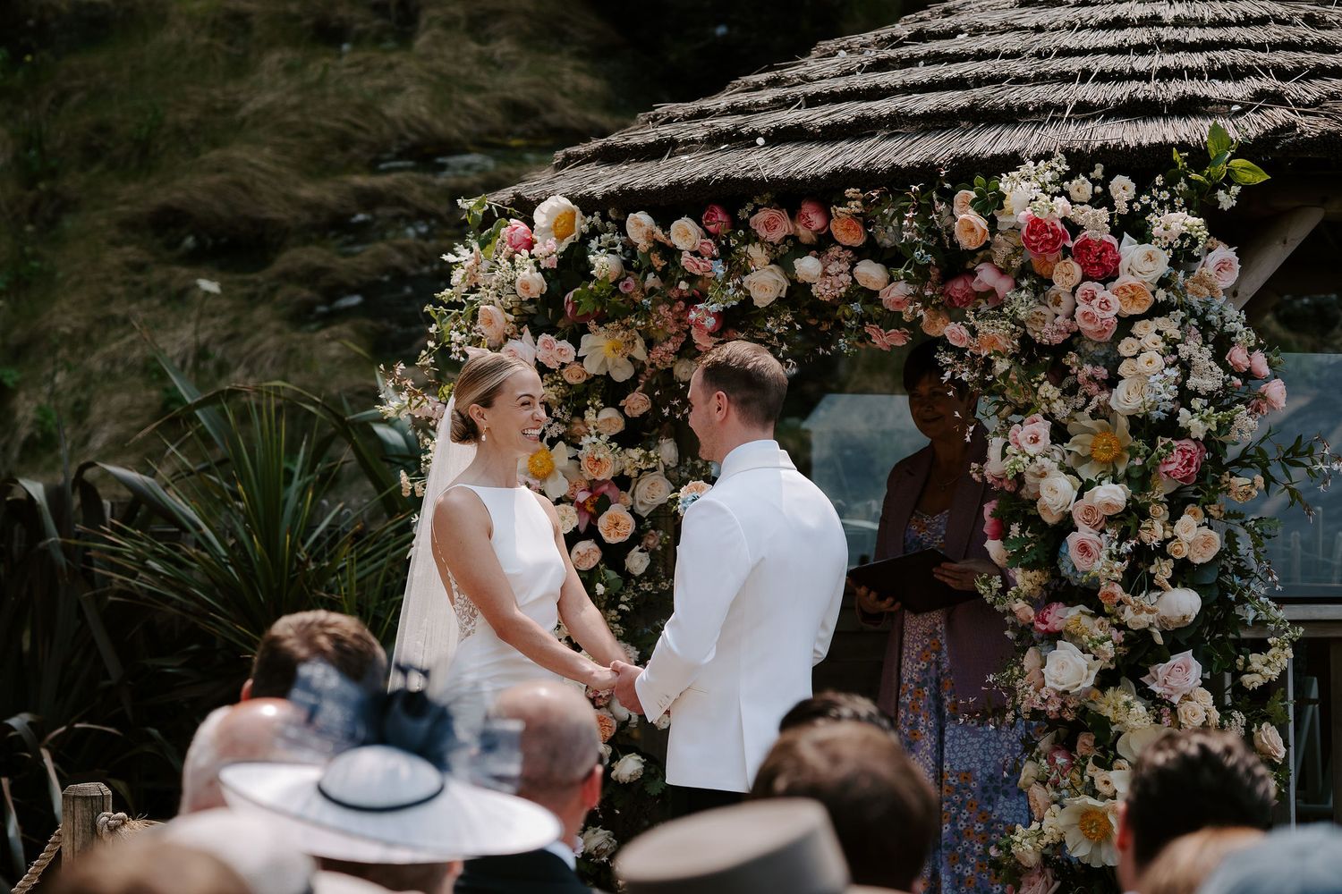 Bride and Groom in front of floral arch next to the sea at Tunnels Beach Wedding Venue in North Devon
