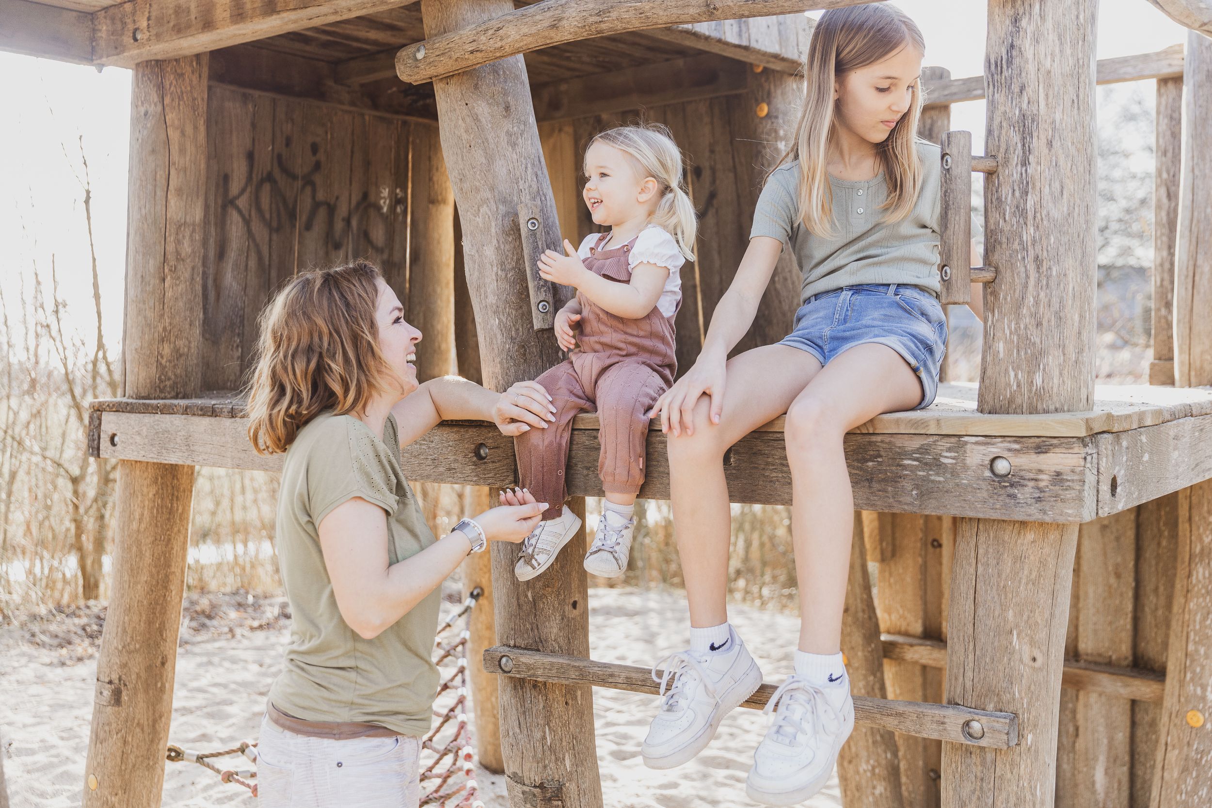 Group relaxing together on wooden structure outdoors. Gezinnen zoals ze zijn fotografie.