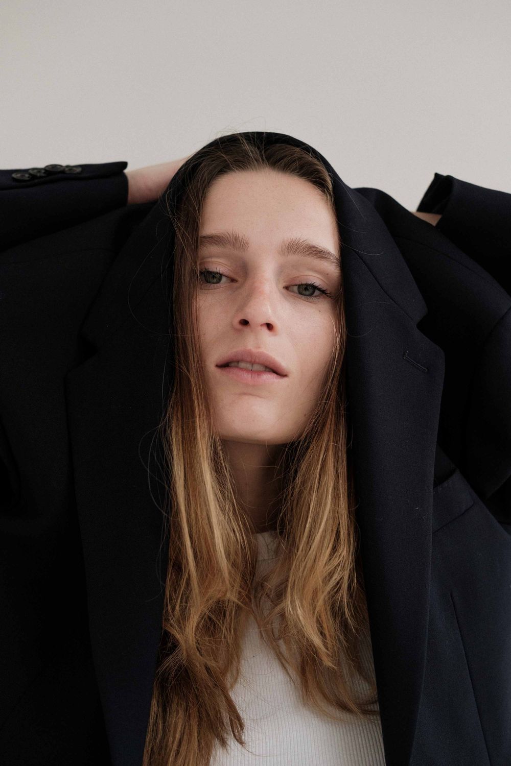 Portrait series showing close-up angles of a model wearing a black blazer and white top with flowing brown hair.