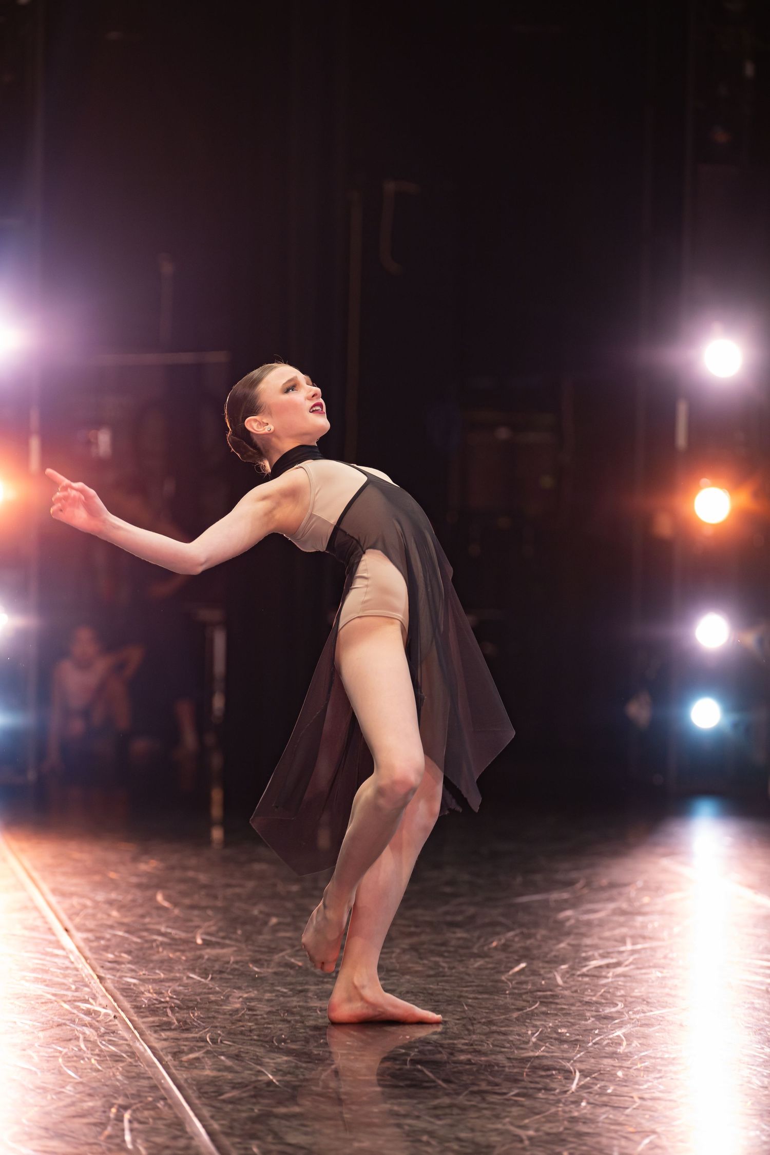 Dramatic dance performance on dark stage with dramatic lighting effects.