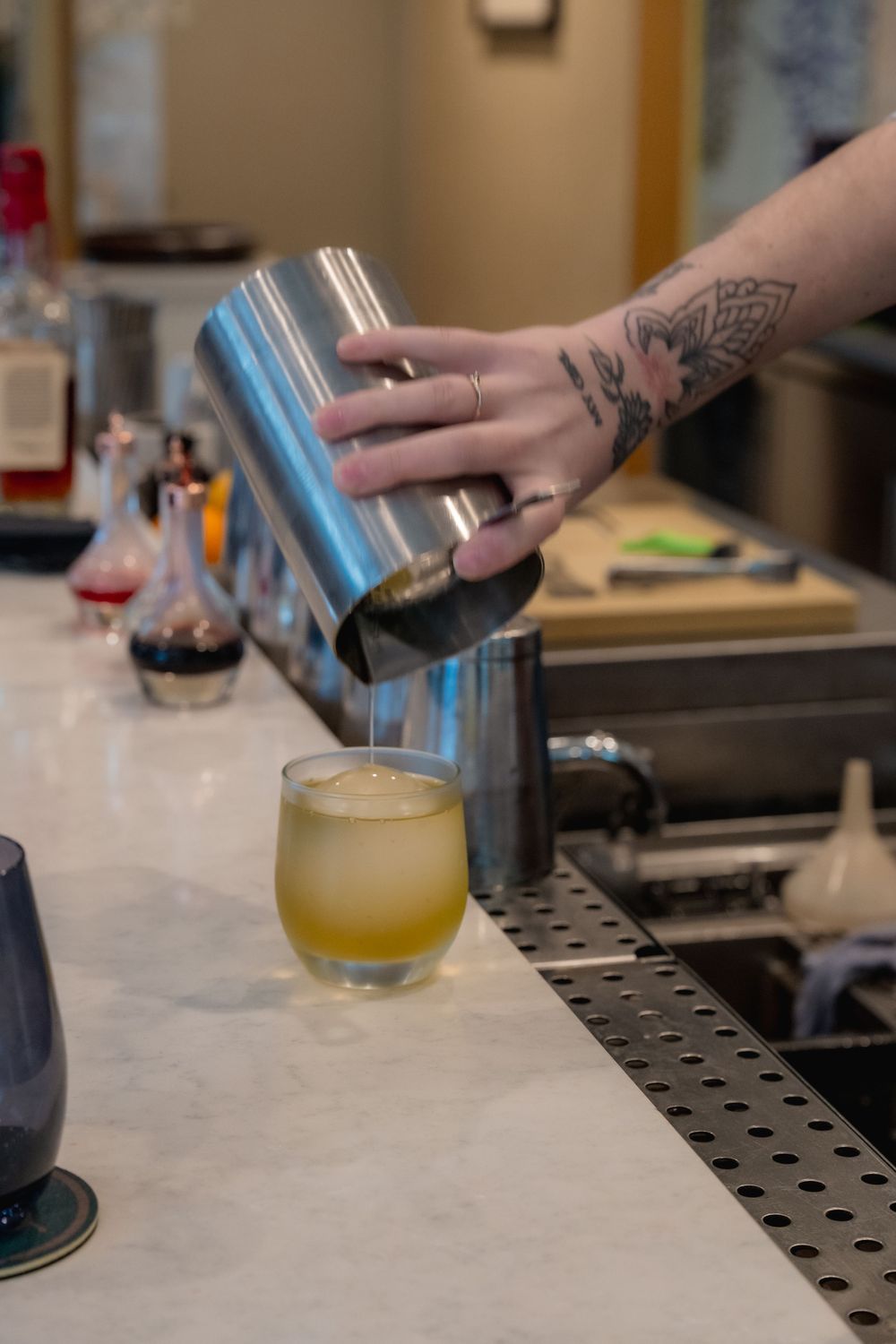Close up of bartender making a drink and pouring it into a glass