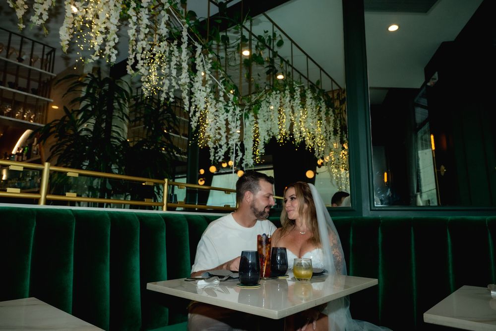 Newlywed couple snuggling in green velvet booth at Podmore Restaurant in Honolulu.