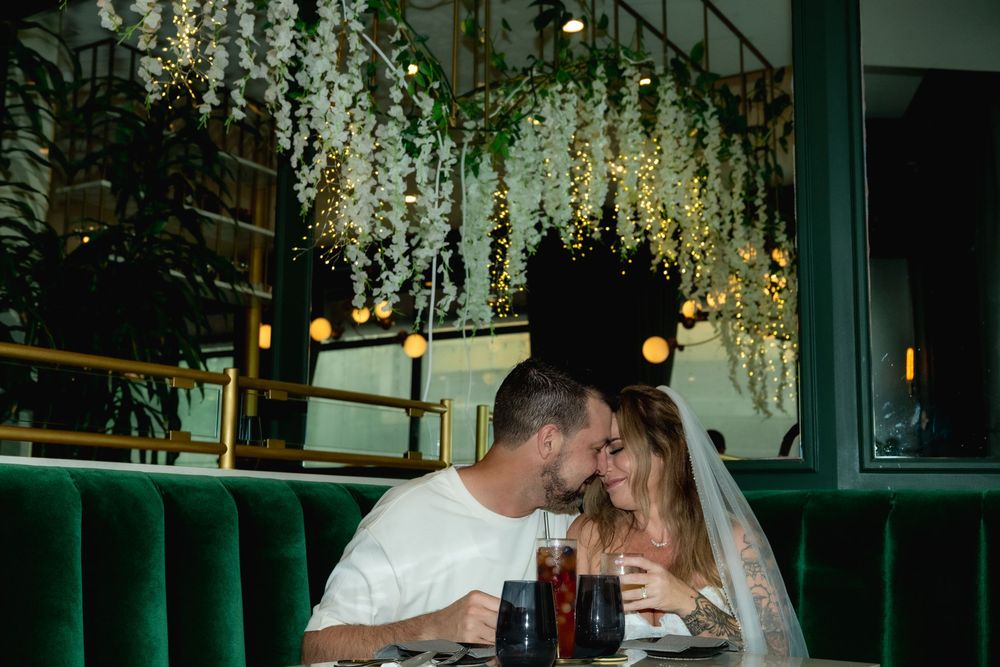 Newlywed couple snuggling in green velvet booth at Podmore Restaurant in Honolulu.