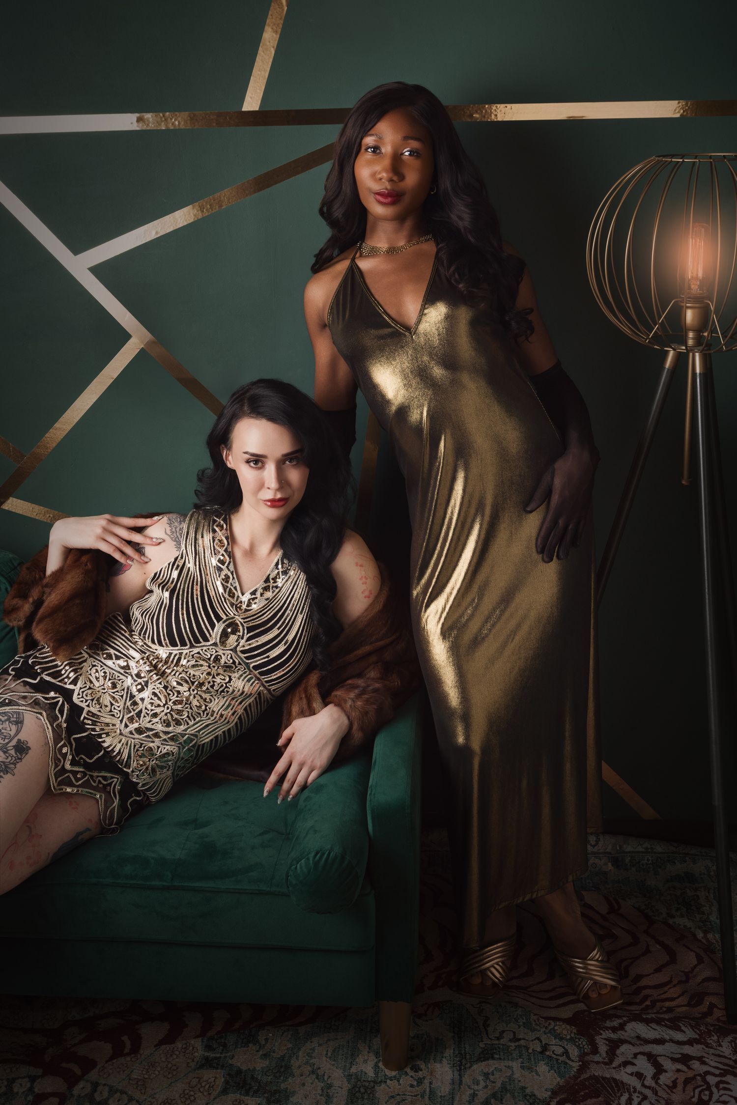 Two elegant women in gold Art Deco outfits pose in a green and gold styled room.