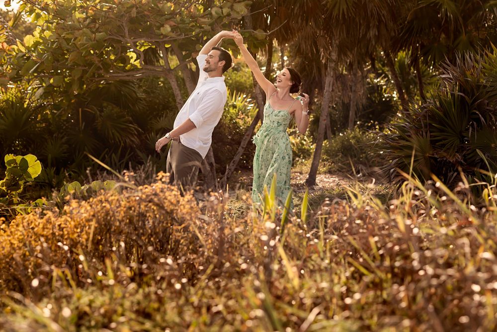 Couple dancing together in a sun-drenched tropical garden surrounded by lush greenery.